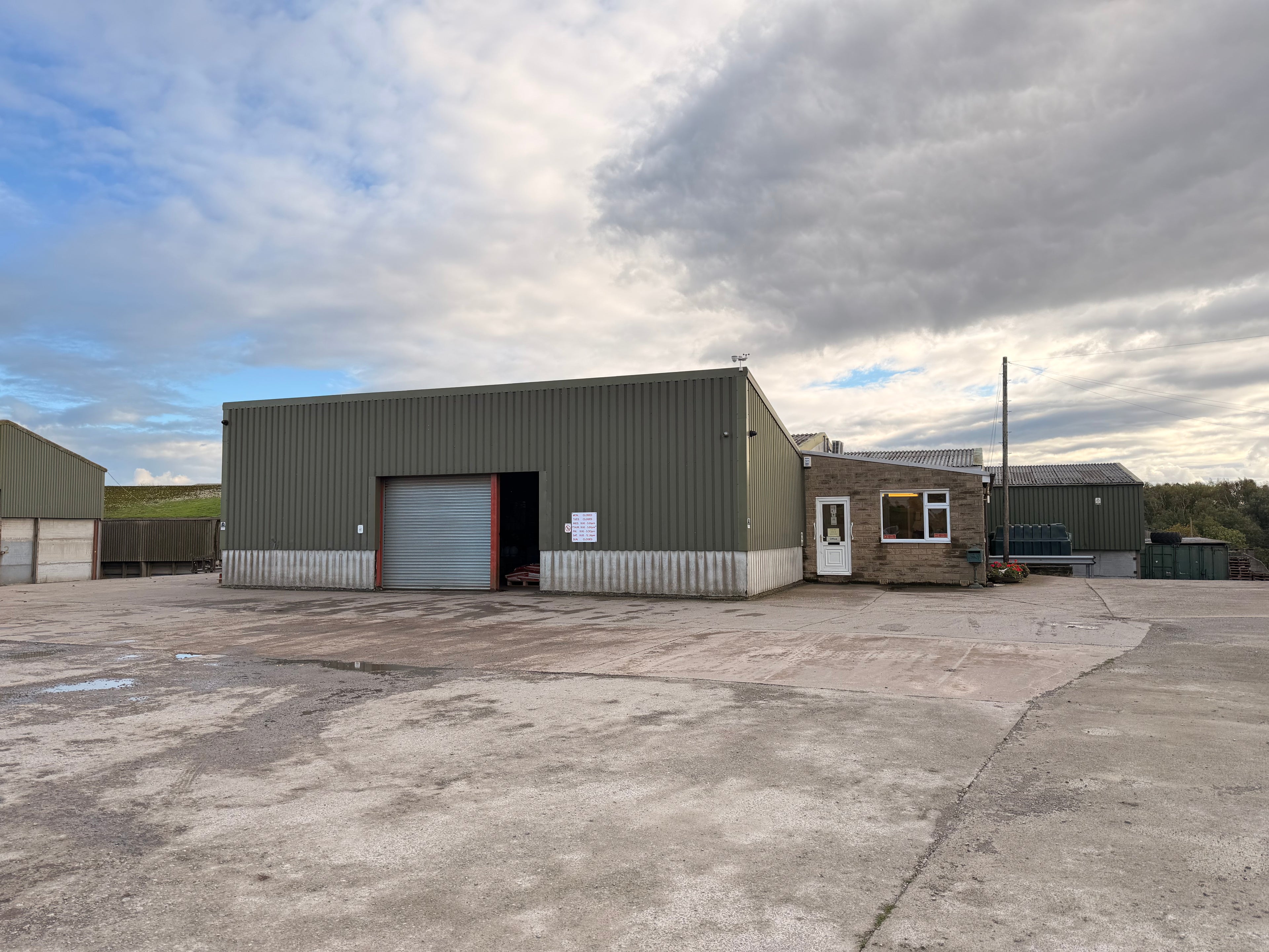 Industrial building with a large garage door under a cloudy sky.